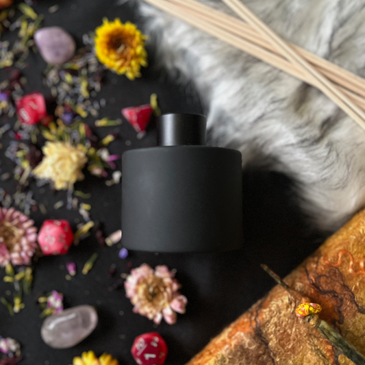 Black matte diffuser bottle on a black background with dried flowers and crystals
